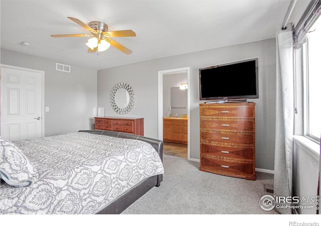 carpeted bedroom with visible vents, ensuite bathroom, and ceiling fan