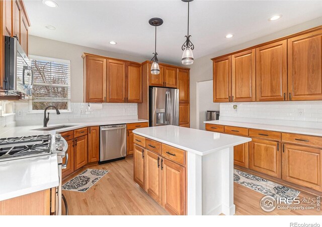 kitchen featuring appliances with stainless steel finishes, light wood-style floors, light countertops, and a sink