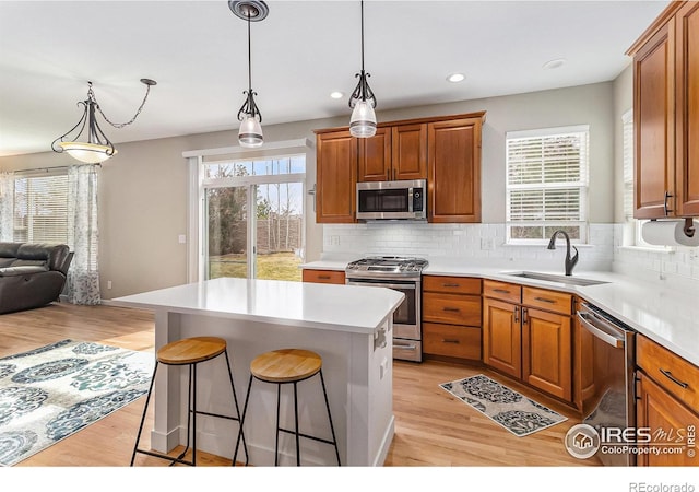 kitchen with stainless steel appliances, a breakfast bar, a sink, light countertops, and tasteful backsplash