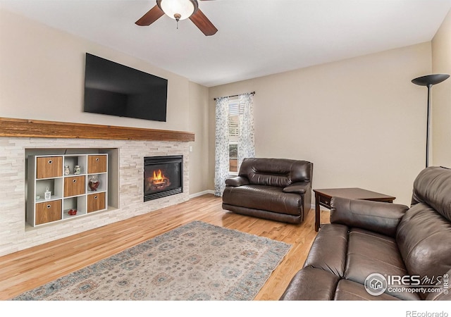 living area with ceiling fan, a fireplace, and wood finished floors