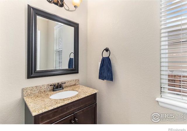 bathroom featuring a textured wall and vanity