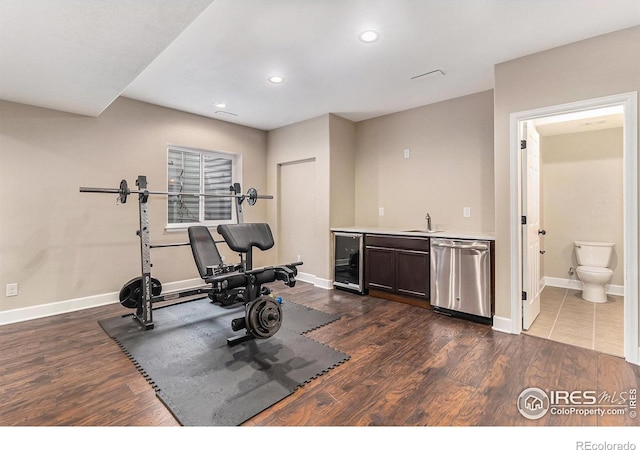 exercise area featuring wine cooler, baseboards, dark wood finished floors, and indoor wet bar