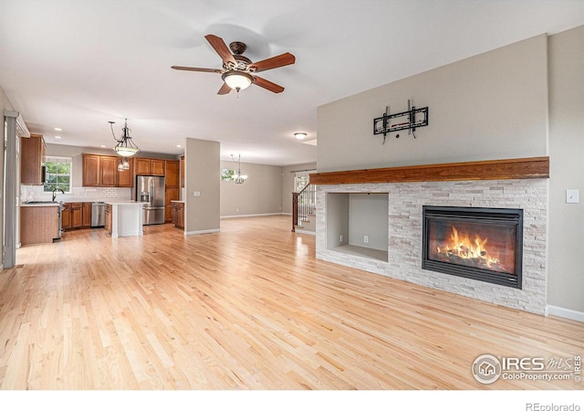 4910 Crimson Star Dr, Broomfield, CO 80023 - unfurnished living room featuring light wood finished floors, a fireplace, stairs, ceiling fan, and a chandelier