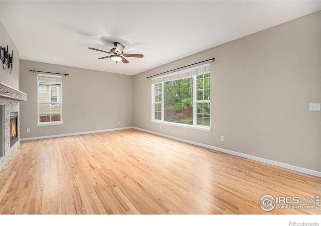 4910 Crimson Star Dr, Broomfield, CO 80023 - unfurnished living room with light wood-type flooring, healthy amount of natural light, a ceiling fan, and a stone fireplace