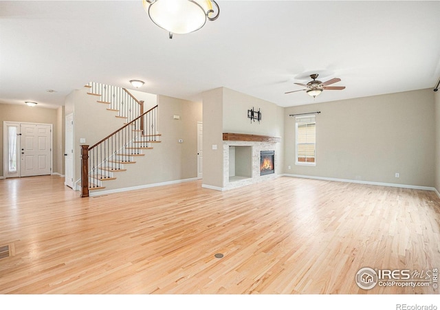 4910 Crimson Star Dr, Broomfield, CO 80023 - unfurnished living room with light wood-type flooring, stairway, a ceiling fan, and a fireplace