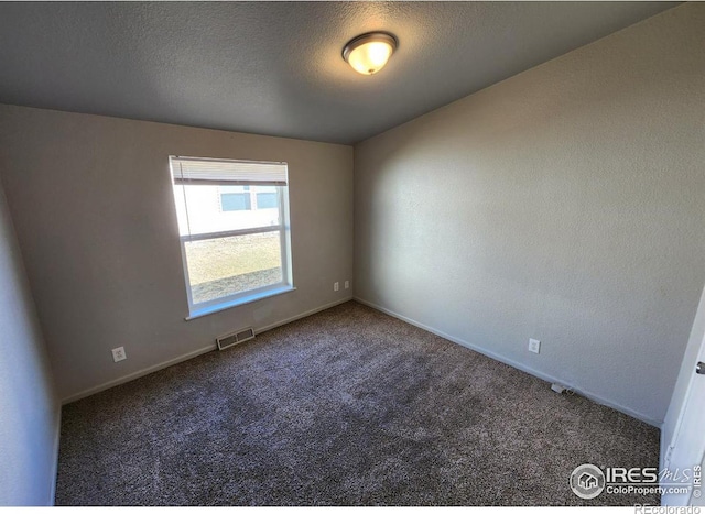 carpeted spare room featuring baseboards, visible vents, and a textured ceiling