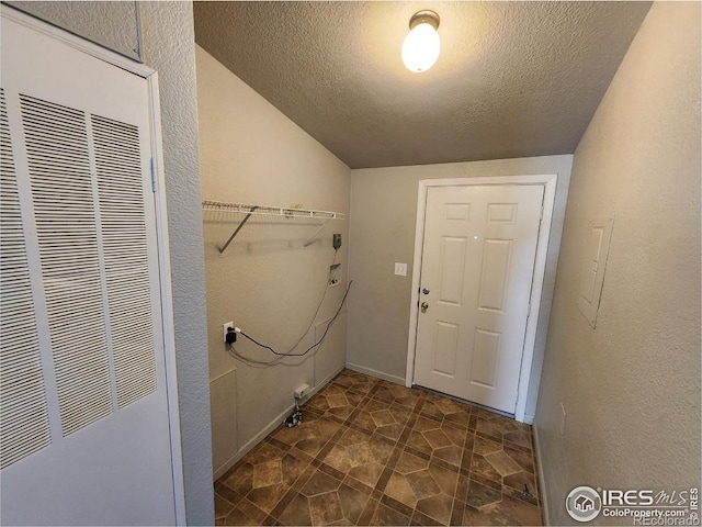 laundry room with laundry area, a heating unit, a textured ceiling, and a textured wall