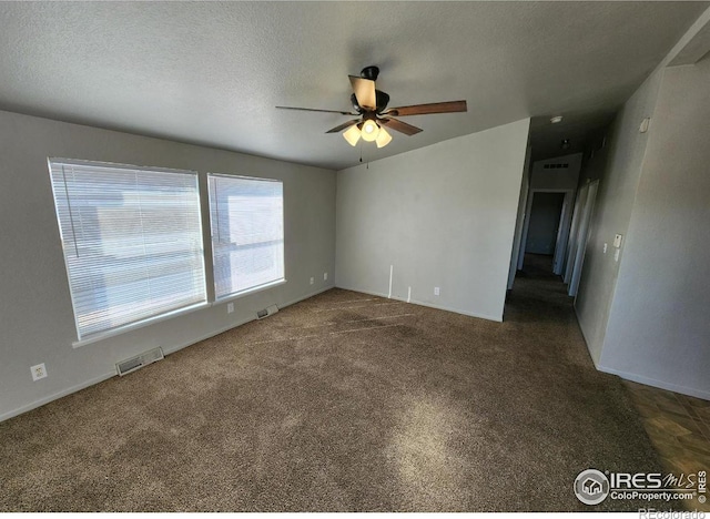 carpeted empty room with visible vents, ceiling fan, and a textured ceiling