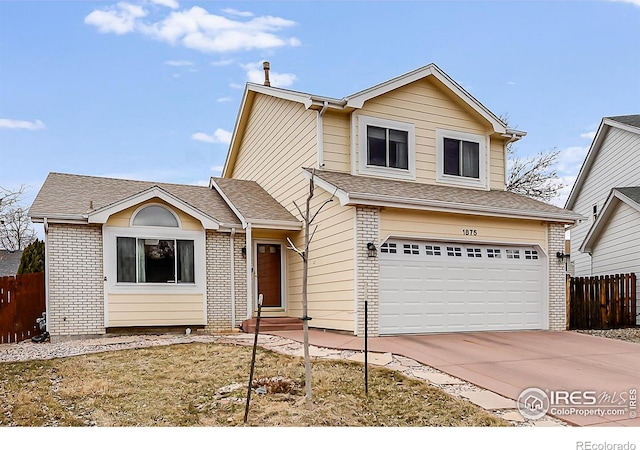 traditional-style house with a garage, concrete driveway, brick siding, and fence