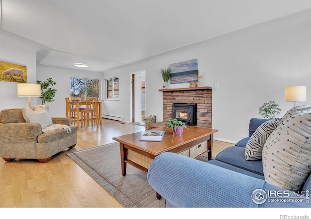 living room featuring a baseboard radiator, light wood-style flooring, and baseboards