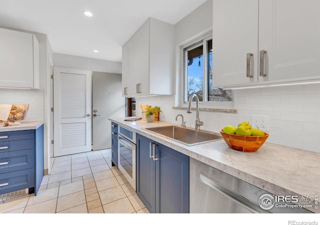 kitchen featuring appliances with stainless steel finishes, light countertops, blue cabinetry, a sink, and recessed lighting