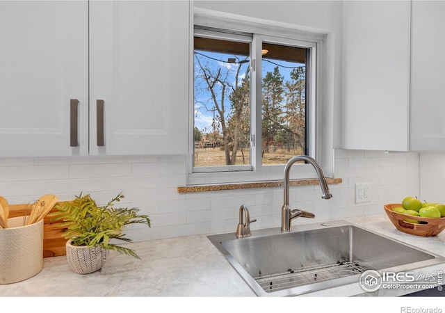 kitchen featuring white cabinets, a sink, and decorative backsplash