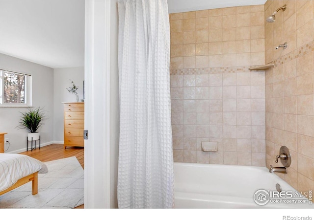 full bathroom featuring baseboards, wood finished floors, and shower / tub combo with curtain