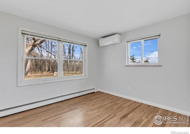 empty room with a baseboard radiator, baseboards, light wood-style flooring, and an AC wall unit