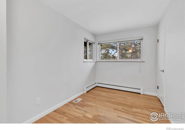 spare room featuring light wood finished floors, visible vents, baseboards, and baseboard heating