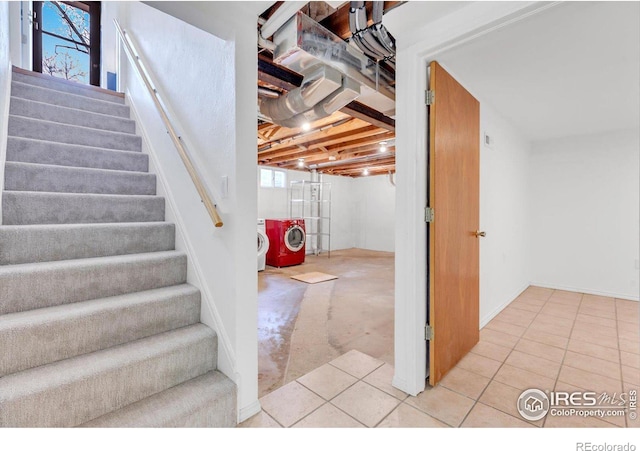 basement with stairway, separate washer and dryer, and light tile patterned flooring