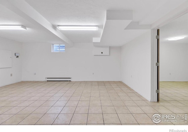 basement featuring a textured ceiling, baseboard heating, and light tile patterned flooring