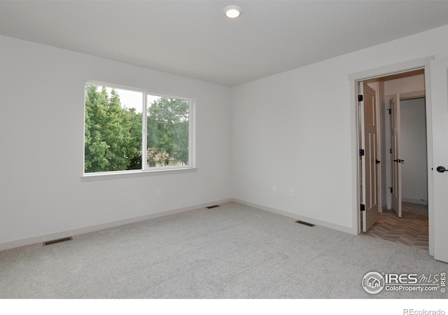 carpeted spare room with visible vents and baseboards