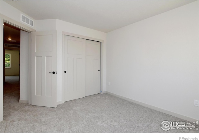 unfurnished bedroom with carpet floors, a closet, visible vents, and baseboards