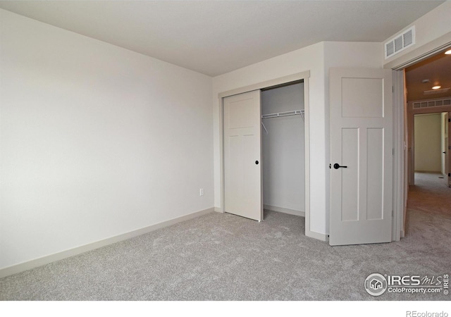 unfurnished bedroom featuring baseboards, visible vents, a closet, and light colored carpet