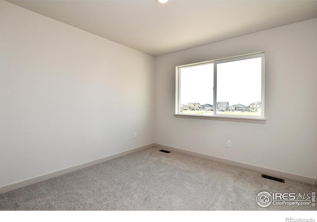 carpeted spare room featuring baseboards and visible vents