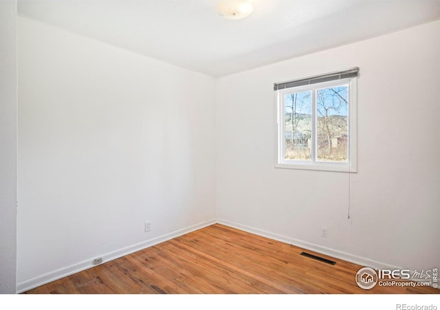 empty room featuring visible vents, baseboards, and wood finished floors