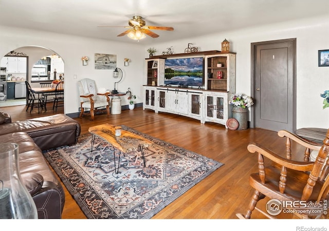 living area featuring arched walkways, ceiling fan, and wood finished floors