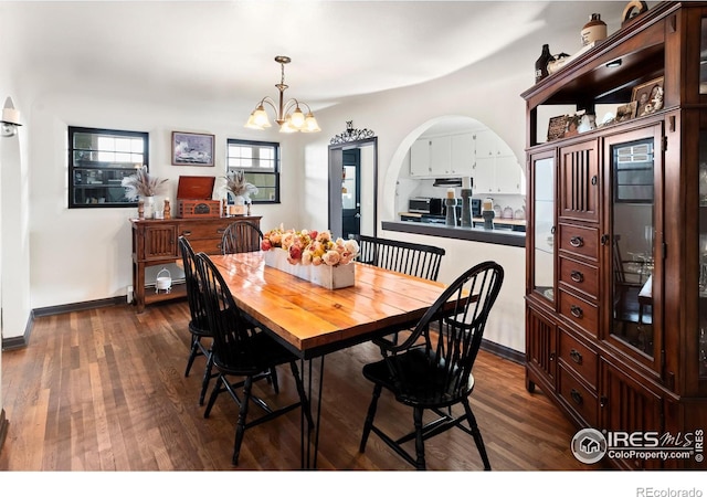 dining space with arched walkways, dark wood-style flooring, a notable chandelier, and baseboards