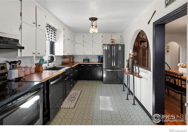 kitchen featuring dishwashing machine, freestanding refrigerator, under cabinet range hood, black range with electric cooktop, and white cabinetry