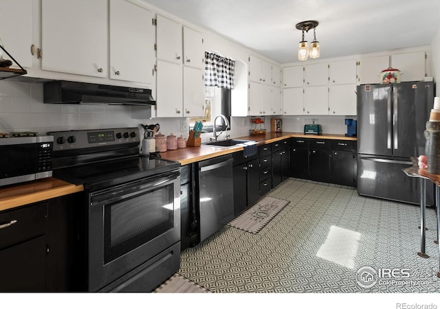 kitchen featuring under cabinet range hood, stainless steel appliances, a sink, white cabinets, and dark cabinetry