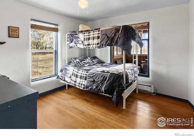 bedroom with baseboards, baseboard heating, and wood finished floors