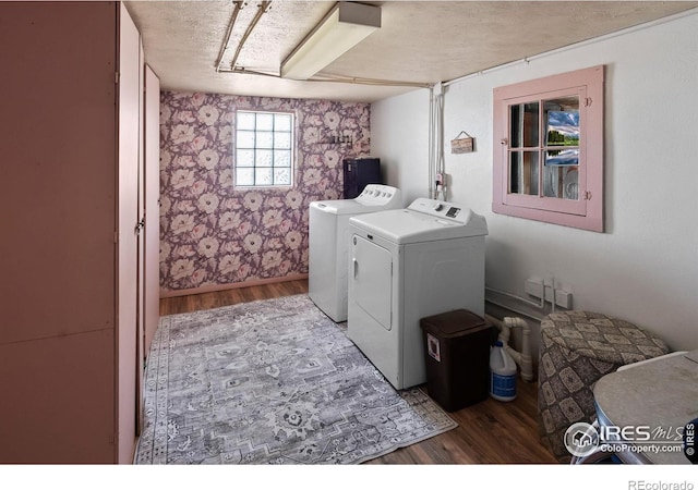 clothes washing area with a textured ceiling, laundry area, wood finished floors, and washing machine and dryer