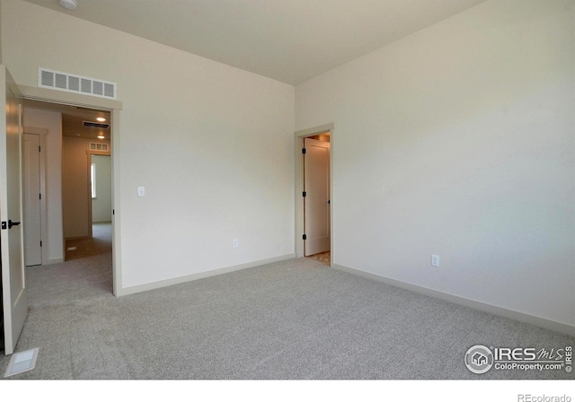 carpeted empty room with visible vents and baseboards