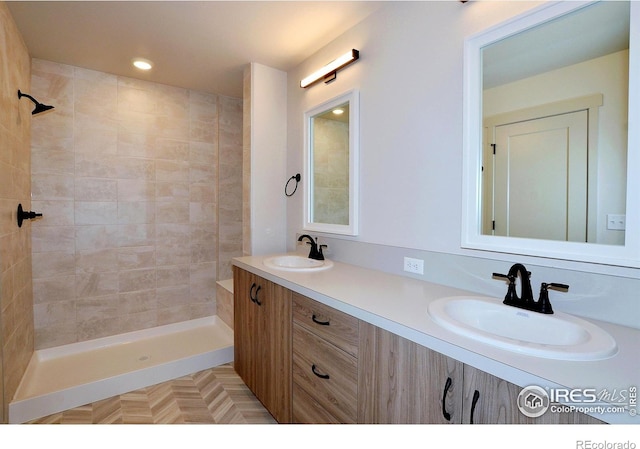 bathroom with recessed lighting, tiled shower, a sink, and double vanity