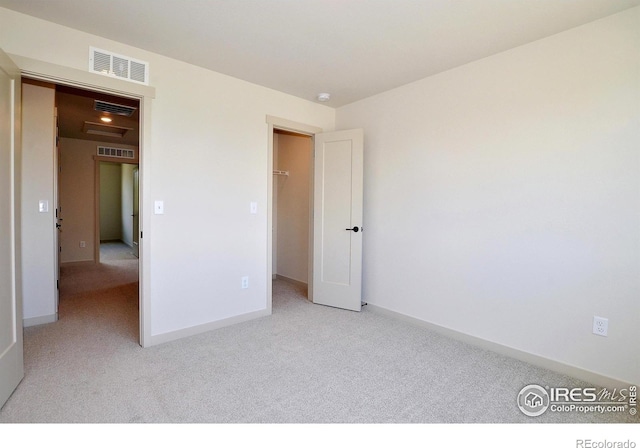 unfurnished bedroom featuring baseboards, visible vents, attic access, and light colored carpet