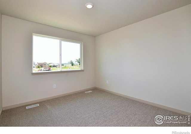 carpeted spare room with visible vents and baseboards