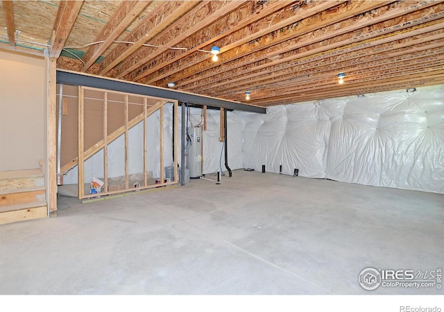 unfinished basement featuring stairway and electric water heater