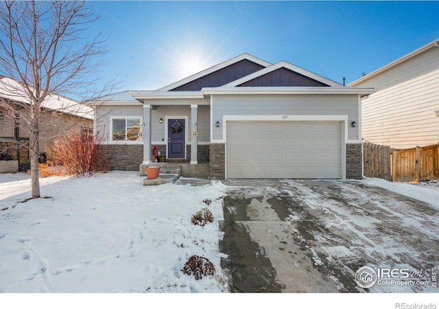 view of front of house with an attached garage, stone siding, fence, and board and batten siding