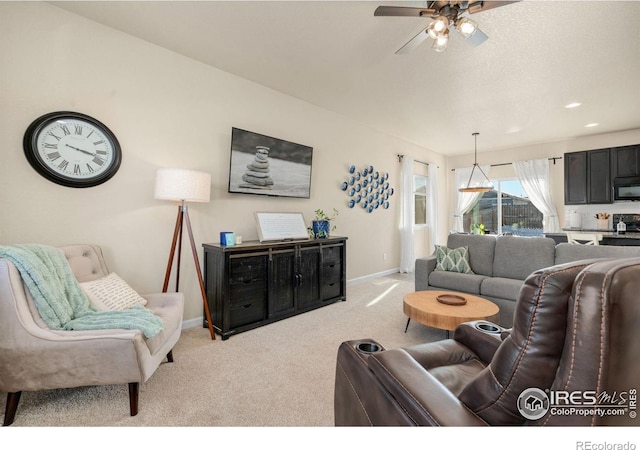 living area featuring baseboards, ceiling fan, and light colored carpet