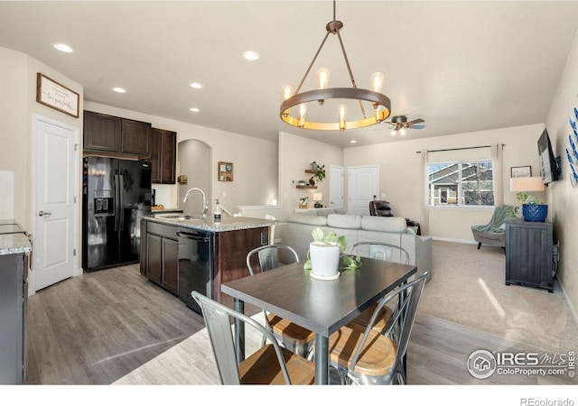 dining area featuring arched walkways, recessed lighting, light wood-style flooring, baseboards, and ceiling fan with notable chandelier