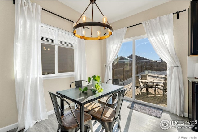 dining area with baseboards, light wood-style flooring, and an inviting chandelier