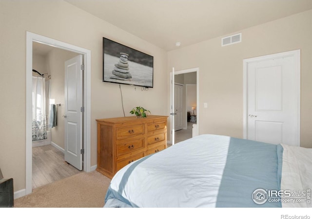 bedroom featuring baseboards, connected bathroom, visible vents, and light colored carpet