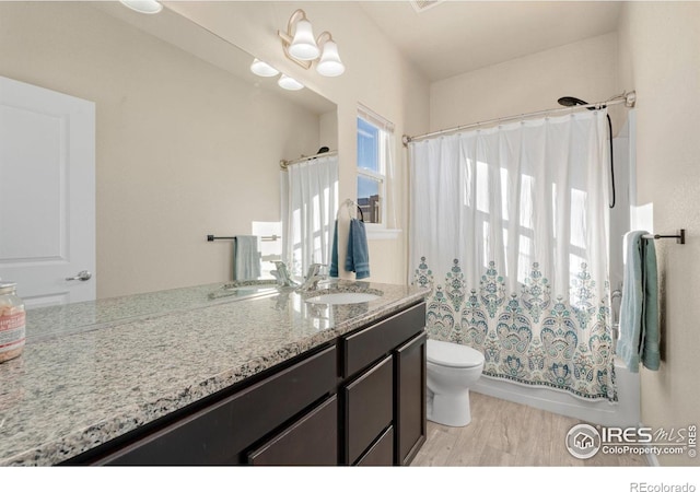 full bath with toilet, shower / bathtub combination with curtain, wood finished floors, and vanity