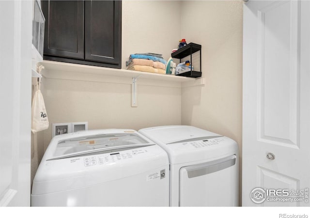 clothes washing area with cabinet space and separate washer and dryer