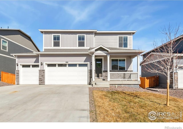 view of front of house featuring an attached garage, covered porch, concrete driveway, stone siding, and board and batten siding