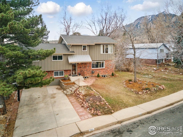 split level home featuring driveway, brick siding, and board and batten siding