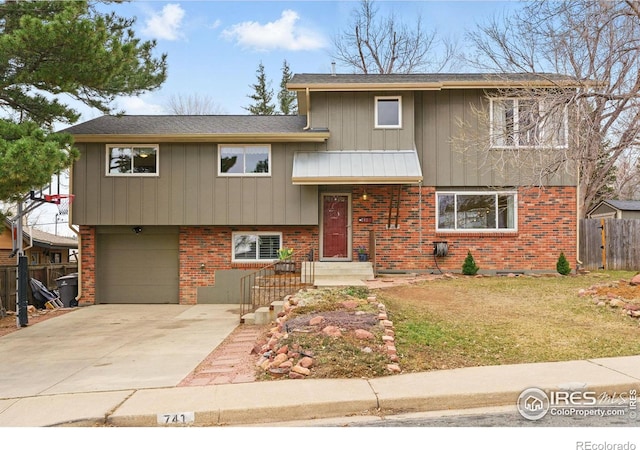 split level home with brick siding, an attached garage, a front yard, fence, and driveway