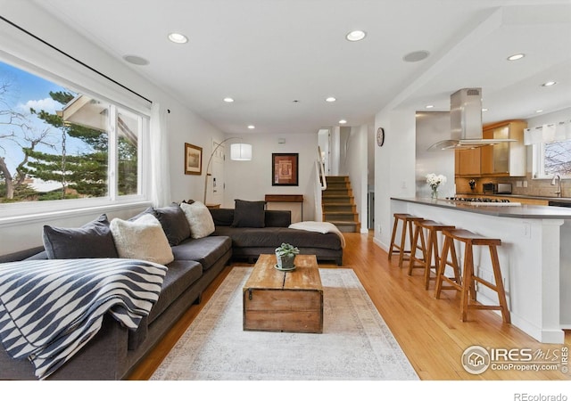 living room with light wood-style floors, baseboards, stairway, and recessed lighting