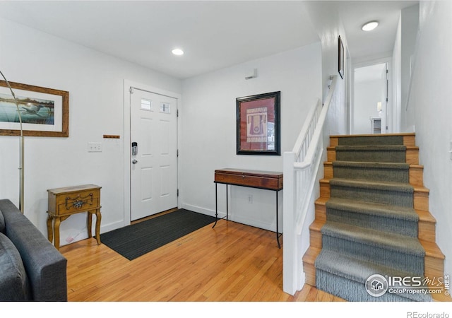 entryway with light wood-type flooring, baseboards, stairway, and recessed lighting