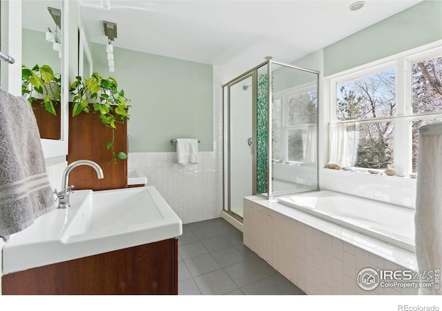 bathroom with tile walls, tile patterned floors, vanity, a shower stall, and a bath